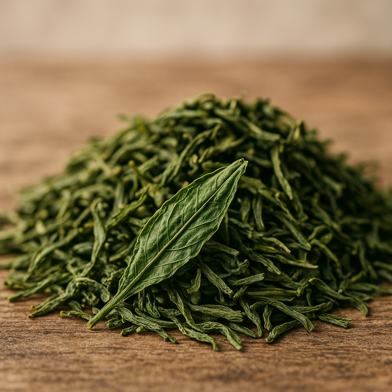 Vibrant dry green leaf green tea showing whole leaf texture on a wooden surface with soft natural lighting.