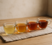 Side-by-side comparison of brewed tea infusions in clear glass cups on a wooden table with natural lighting.